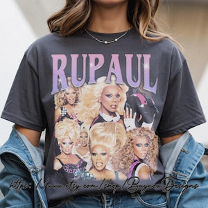 以下が含まれることがあります： RuPaulの画像コラージュと「RUPAUL」のグラデーションパープルとピンクのフォントが特徴のダークグレーTシャツ。このシャツはヴィンテージ感があり、象徴的なドラァグクイーンへのトリビュートです。