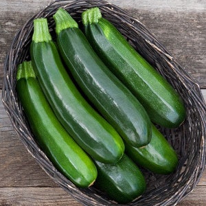 Op de afbeelding: Een mand gevuld met vijf groene courgettes.