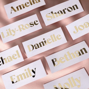 May include: White cards with gold foil lettering for names such as Amelia, Lily-Rose, Sharon, Danielle, Michael, Emily, Bethan, Molly, and Joa.
