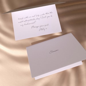 May include: Two white invitation cards with cursive text. One card reads "laugh with me and help make this the most unforgettable day? Will you be my bridesmaid? Always your girl. Molly +." The other card says "Shannon."