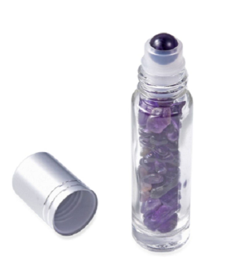 May include: A clear glass roller bottle filled with amethyst crystals and a silver cap. The bottle has a roller ball applicator.