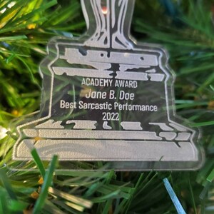 Puede incluir: Un premio de pl&aacute;stico plateado con forma de persona sosteniendo una espada. La base del premio dice "ACADEMY AWARD Jane B. Doe Best Sarcastic Performance 2022".