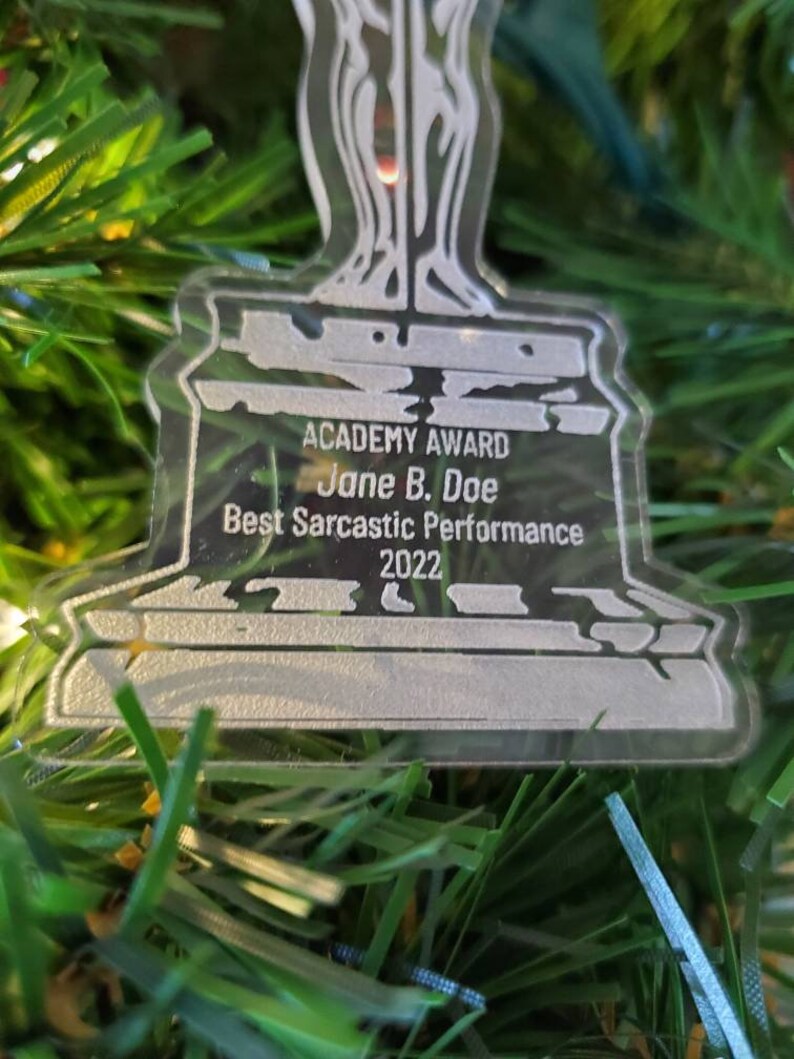 Puede incluir: Un premio de pl&aacute;stico plateado con forma de persona sosteniendo una espada. La base del premio dice "ACADEMY AWARD Jane B. Doe Best Sarcastic Performance 2022".