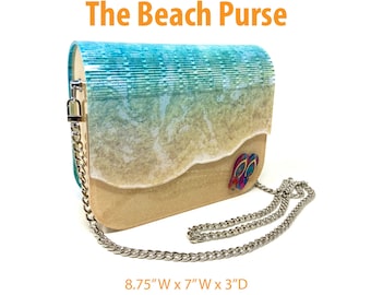 Puede incluir: Un bolso de playa con una base marrón claro, un diseño de olas azul y blanco y un par de chanclas en la parte delantera. El bolso tiene una correa de cadena plateada y mide 22,2 cm de ancho por 17,8 cm de ancho por 7,6 cm de profundidad. El texto "The Beach Purse" está en la parte superior de la imagen y "File Formats Included: SVG • PDF • DXF • EPS" está en la parte inferior de la imagen.