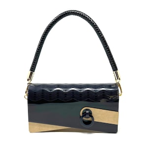 Puede incluir: Un bolso de mano negro y marrón con textura ondulada y un detalle de anillo dorado. El bolso tiene una correa trenzada negra.