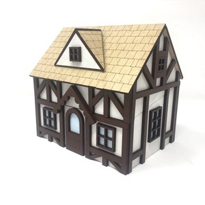 Puede incluir: Un modelo de casa en miniatura de madera con un exterior marrón y blanco, un techo marrón y varias ventanas. La casa tiene una moldura decorativa festoneada sobre la puerta principal.