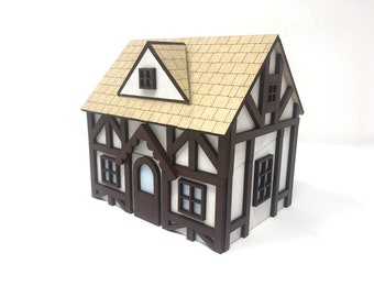 May include: A miniature wooden model of a house with a brown and white exterior, a brown roof, and multiple windows. The house has a decorative, scalloped trim above the front door.
