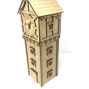 Può includere: Un modello in legno di una torre dell'orologio con un quadrante dell'orologio, una piccola finestra e quattro finestre al livello inferiore. La torre è realizzata in legno marrone chiaro e ha un effetto pietra testurizzato.