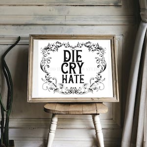 May include: A framed print with a white background and black ornate border. The text "DIE CRY HATE" is printed in bold black letters inside the border.