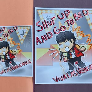 May include: Two square prints featuring a cartoon character with a microphone, wearing a red jacket and sunglasses. The text "SHUT UP AND GO TO BED" and "VIVA LAS VENGEANCE" are written in red. The background has a stage-like design.