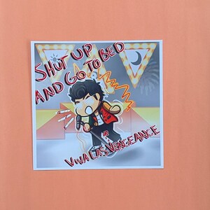 May include: Square sticker with a cartoon illustration of a person holding a microphone, with the text "Shut Up and Go To Bed" and "Viva Las Vengeance". The character is wearing a red jacket and black pants. The background is a mix of yellow, orange, and gray.