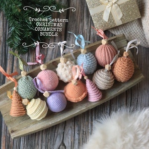 Op de afbeelding: Een verzameling van 12 gehaakte kerstversieringen in verschillende kleuren, waaronder roze, blauw, groen, geel en oranje. De versieringen zijn gerangschikt op een houten dienblad en omvatten een verscheidenheid aan vormen, zoals ballen, kegels en sterren. De tekst "Crochet pattern CHRISTMAS ORNAMENTS BUNDLE" is zichtbaar in de afbeelding.