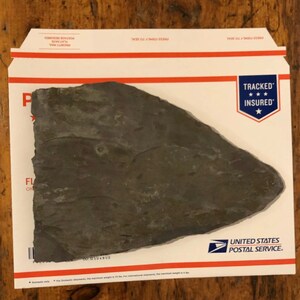 May include: A dark gray, irregularly shaped slate rock with a rough texture. The rock has a natural, organic look and is approximately 12.5 inches by 9.5 inches.