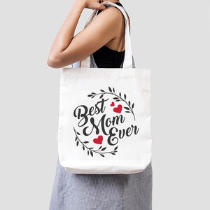 May include: White tote bag with black text and red hearts that reads "Best Mom Ever" surrounded by a wreath of leaves.