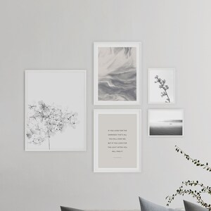 May include: A living room with a light gray couch, two gray pillows, and one striped pillow. There is a coffee table with a stack of books on it. There are four black and white framed prints on the wall behind the couch. The prints feature abstract art, a floral design, and a quote about looking for the light.
