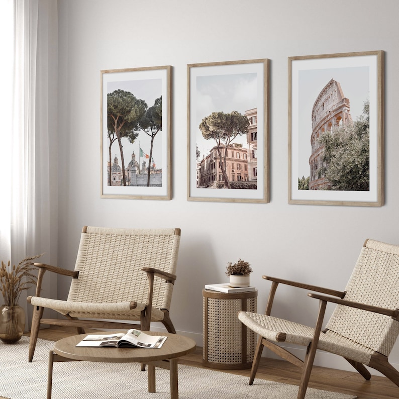 May include: Three framed prints of cityscapes with trees and buildings. The prints are hung on a white wall above a light brown wicker chair and a light brown wicker coffee table.