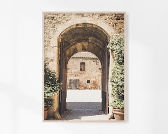 Puede incluir: Un arco de piedra con un edificio rústico en el fondo. El arco está cubierto de enredaderas y el edificio tiene una fachada desgastada.