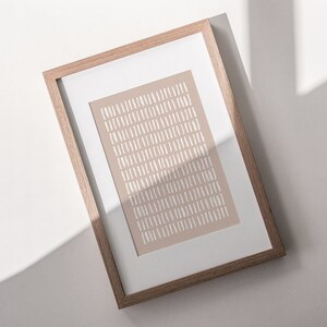 May include: A framed print with a beige background and a pattern of white lines. The frame is made of light brown wood.