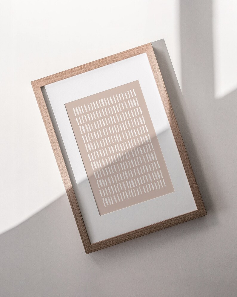 May include: A framed print with a beige background and a pattern of white lines. The frame is made of light brown wood.