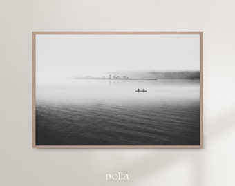 May include: A black and white photograph of a lake with a small boat in the distance. The lake is calm and the sky is overcast. The photo is framed in a wooden frame.