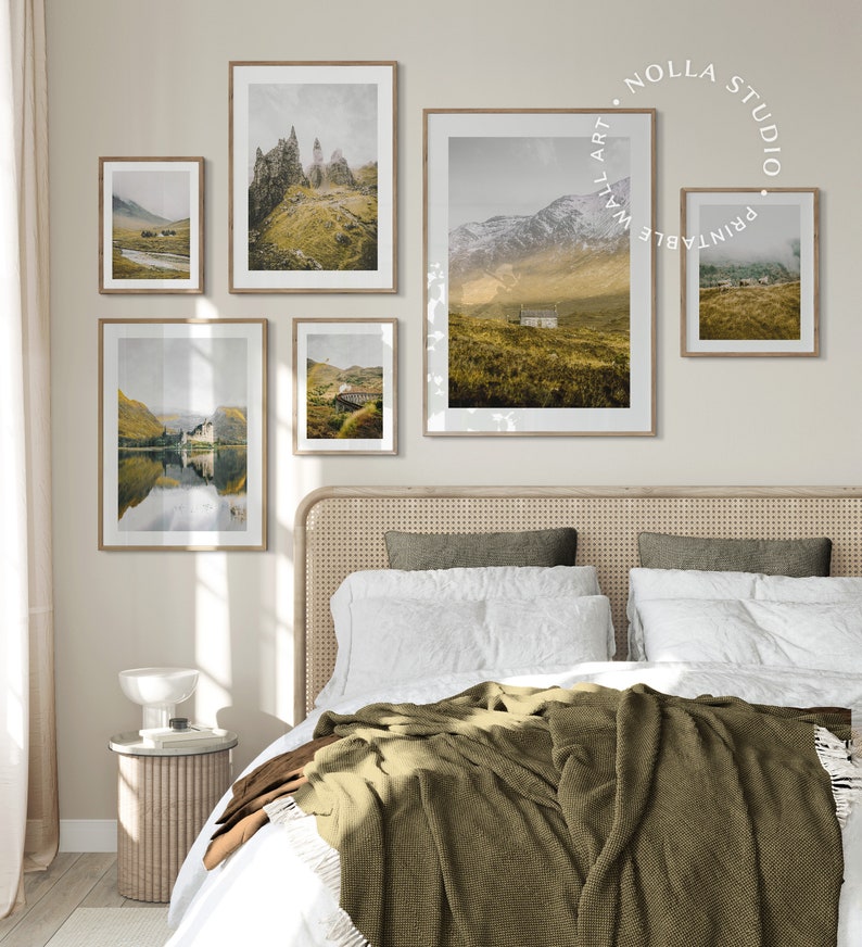 May include: Five framed landscape photographs of mountains, lakes, and fields in Scotland. The photos are hung on a light beige wall above a bed with a white duvet and a green throw blanket.