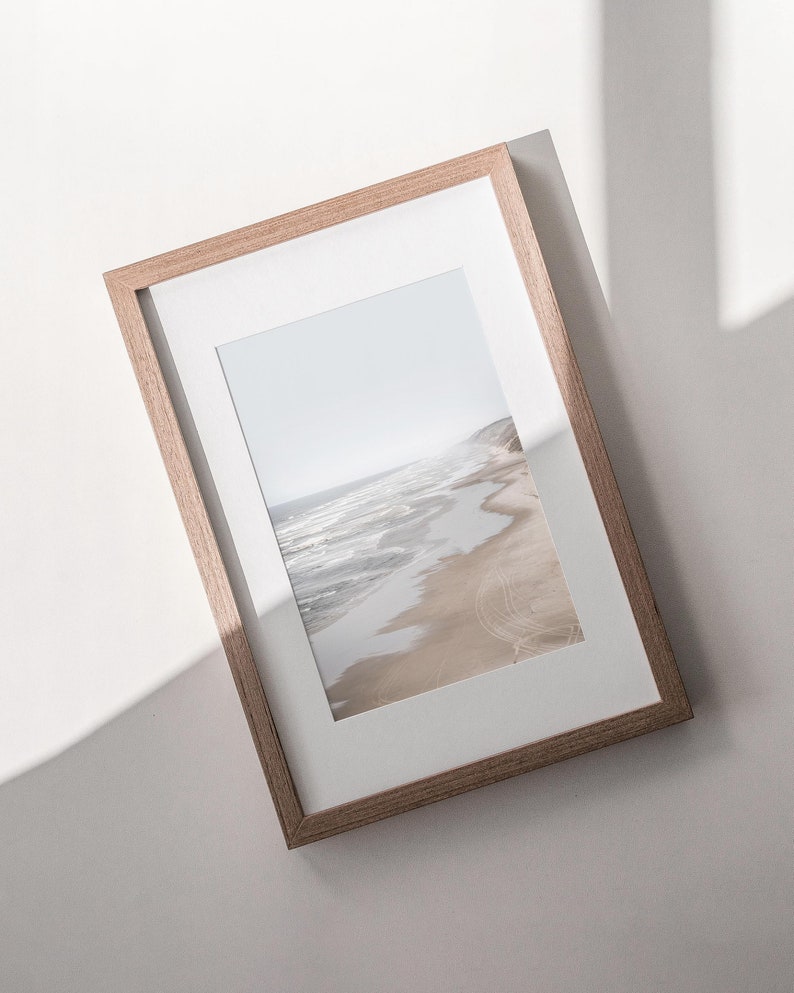 Puede incluir: Una fotograf&iacute;a enmarcada de una escena de playa con olas rompiendo en la orilla y huellas de neum&aacute;ticos en la arena.