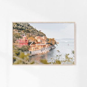 Pu&ograve; includere: Una fotografia di una villa italiana colorata su una scogliera che domina l'oceano. La villa &egrave; dipinta in tonalit&agrave; di giallo, arancione e rosa e ha un tetto in terracotta. L'oceano &egrave; di un blu profondo e il cielo &egrave; di un azzurro chiaro. Alberi e vegetazione verdeggianti circondano la villa.