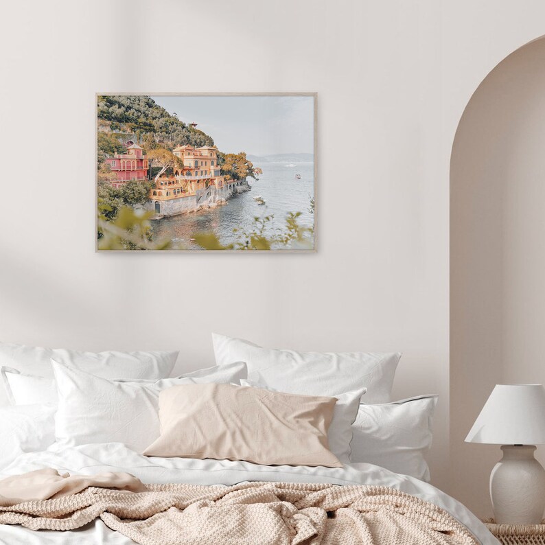 Pu&ograve; includere: Una fotografia incorniciata di una citt&agrave; costiera con edifici colorati su una collina che si affaccia sull'oceano. La foto &egrave; in una cornice di legno chiaro e appesa a una parete bianca.