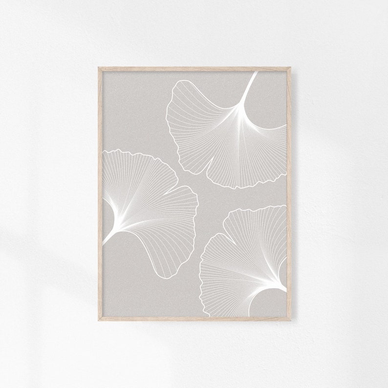 Puede incluir: Una impresi&oacute;n art&iacute;stica enmarcada con tres dise&ntilde;os de hojas de ginkgo blancas sobre un fondo gris claro. Las hojas presentan patrones de venas detallados y est&aacute;n enmarcadas en un marco de madera natural, creando una est&eacute;tica minimalista.