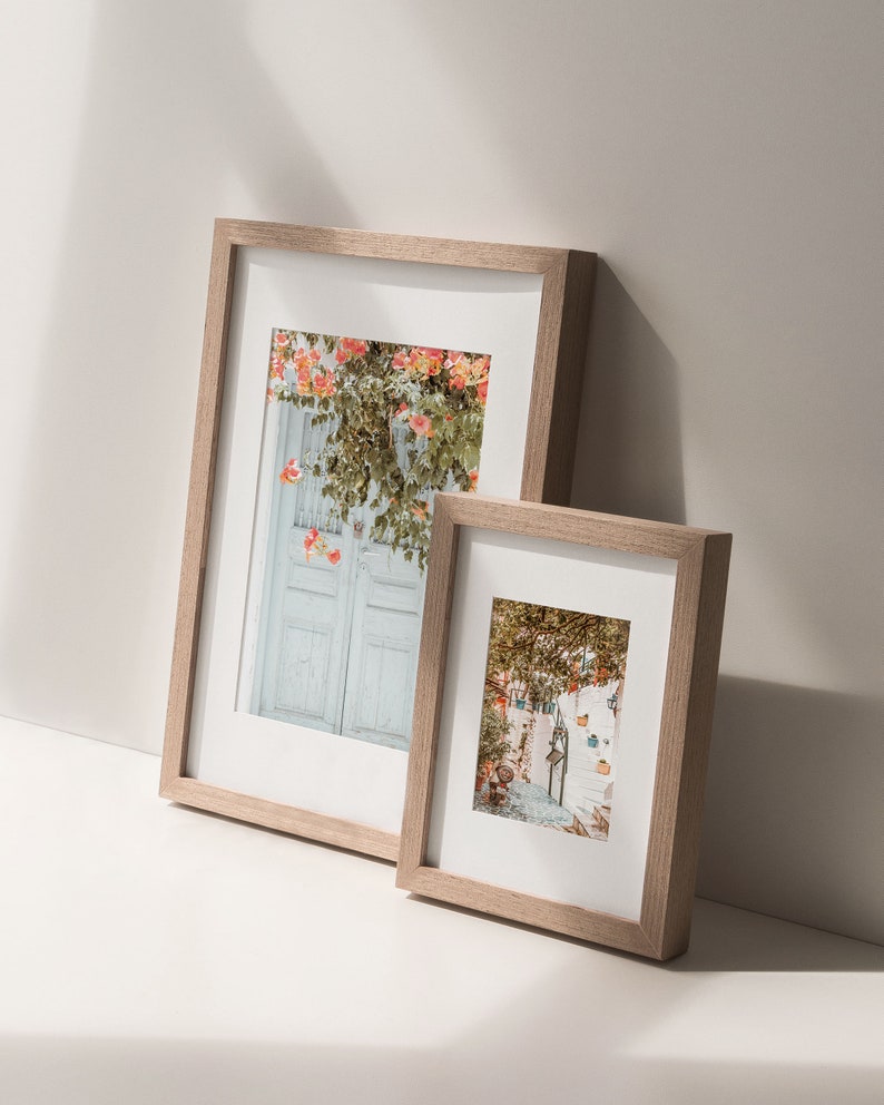 May include: Two wooden picture frames with white mats, one larger than the other, both displaying colorful photographs of a European city scene.