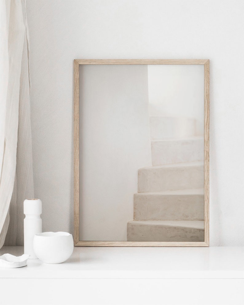 Peut inclure: Une photographie encadr&eacute;e d'un escalier blanc avec un cadre en bois brun clair. La photographie est sur une surface blanche.