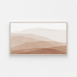 May include: Abstract watercolor painting of a landscape with brown and white hues. The painting is framed in a light wood frame.