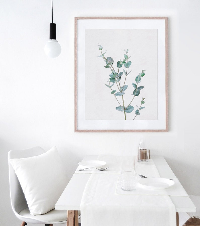 May include: A framed print of a watercolor painting of a eucalyptus branch with green leaves on a white background.
