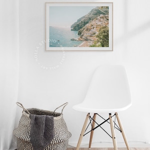 May include: A framed photograph of a coastal town with colorful buildings built into a hillside. The town is situated on a peninsula with a blue ocean in the background. The photo has a vintage, faded look.