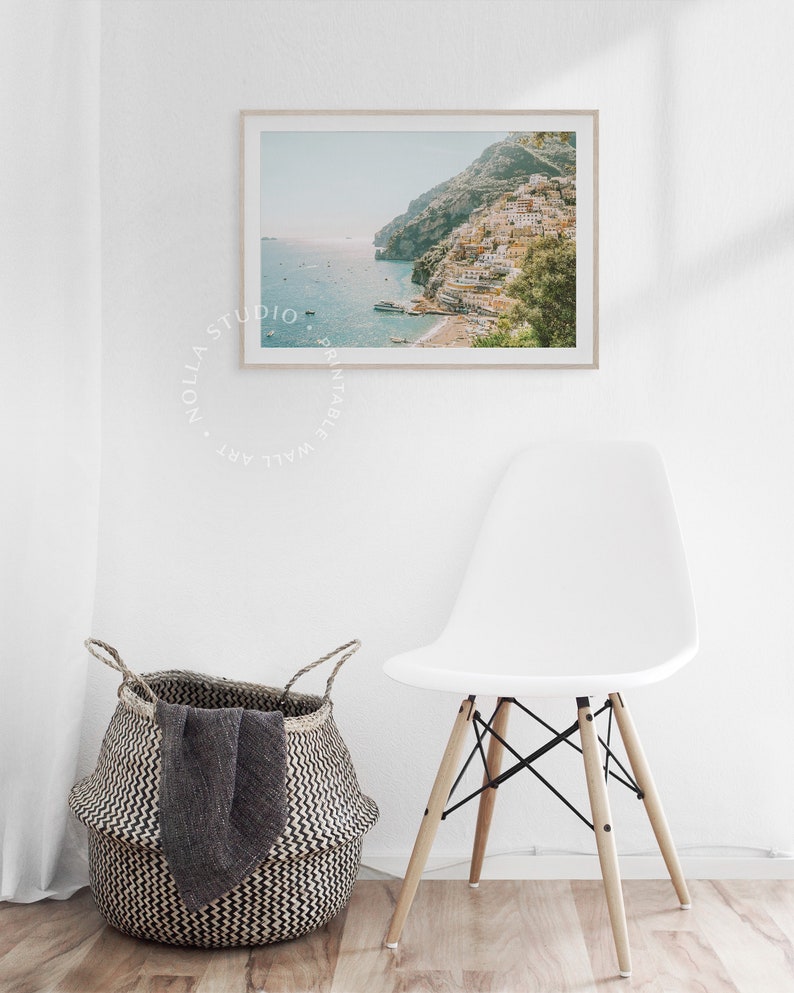 May include: A framed photograph of a coastal town with colorful buildings built into a hillside. The town is situated on a peninsula with a blue ocean in the background. The photo has a vintage, faded look.