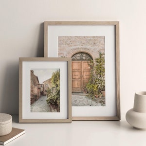 K&ouml;nnte beinhalten: Zwei gerahmte Fotos eines italienischen Dorfes. Das gr&ouml;&szlig;ere Foto zeigt eine Holzt&uuml;r mit einem gew&ouml;lbten Eingang und Topfpflanzen. Das kleinere Foto zeigt eine schmale Kopfsteinpflasterstra&szlig;e mit Geb&auml;uden auf beiden Seiten.