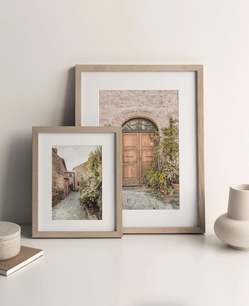 K&ouml;nnte beinhalten: Zwei gerahmte Fotos eines italienischen Dorfes. Das gr&ouml;&szlig;ere Foto zeigt eine Holzt&uuml;r mit einem gew&ouml;lbten Eingang und Topfpflanzen. Das kleinere Foto zeigt eine schmale Kopfsteinpflasterstra&szlig;e mit Geb&auml;uden auf beiden Seiten.