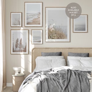 Puede incluir: Un dormitorio con una cama con una manta gris y almohadas blancas. Hay cinco impresiones enmarcadas en la pared sobre la cama. Las impresiones son todas de paisajes marinos y terrestres. El texto "ALSO AVAILABLE IN A SET OF 6" est&aacute; en la pared.