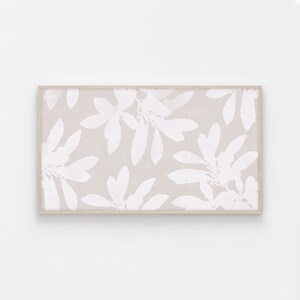 May include: A framed print with a beige background and a white floral pattern. The flowers are stylized and resemble a leaf pattern.