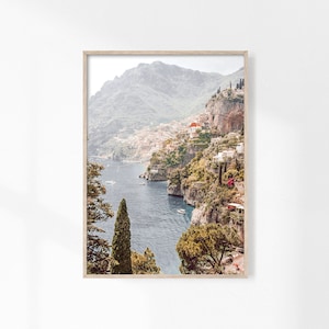 May include: A scenic photograph of a coastal town nestled between lush green cliffs and a sparkling blue sea. The town is built on the slopes of the cliffs, with white buildings and red roofs. The sea is calm and clear, with a few boats visible in the distance.