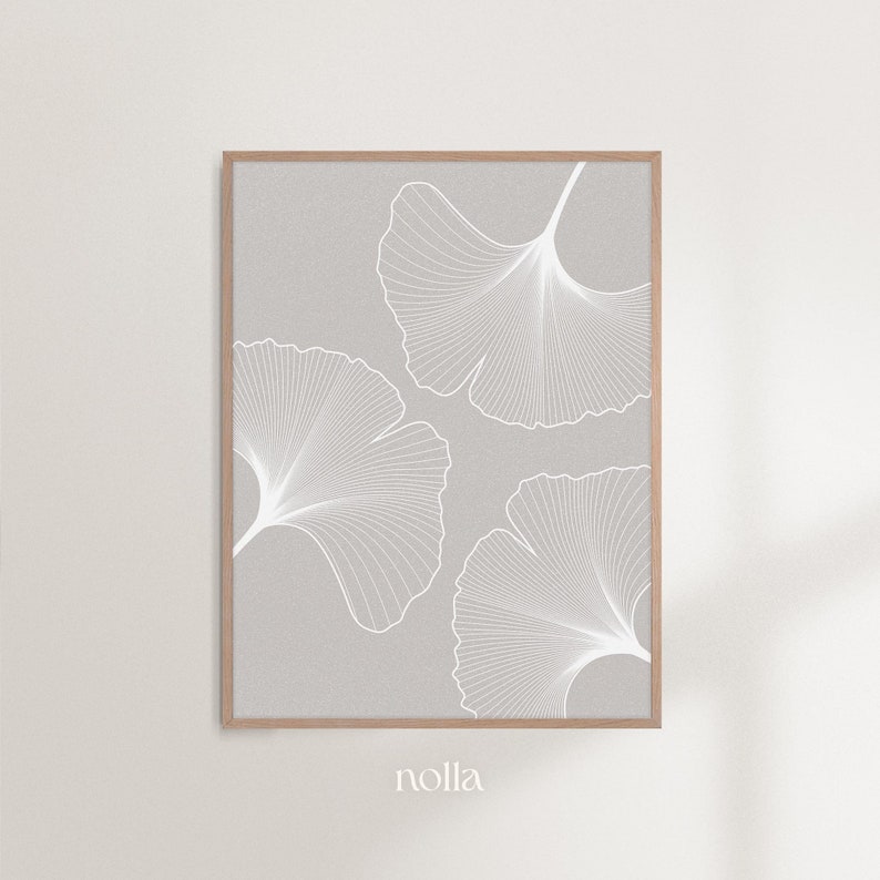 Puede incluir: Una impresi&oacute;n enmarcada con un dise&ntilde;o minimalista de tres hojas de ginkgo blancas sobre un fondo gris claro. Las hojas est&aacute;n detalladas con finas l&iacute;neas blancas, y el marco es de color madera natural. La impresi&oacute;n tiene la palabra "nolla" en la esquina inferior izquierda.