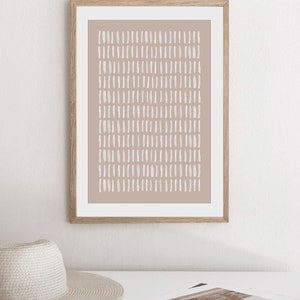 May include: A framed print with a minimalist abstract design. The print features a light brown background with a pattern of white dashes.