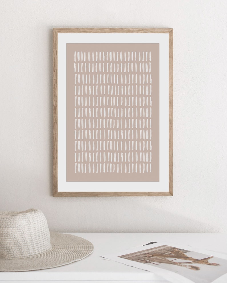 May include: A framed print with a minimalist abstract design. The print features a light brown background with a pattern of white dashes.