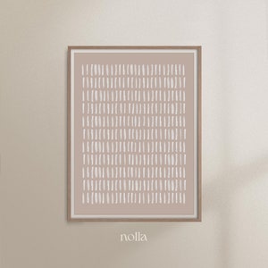 May include: A framed abstract print with a light brown background and a pattern of white brushstrokes. The print is framed in a natural wood frame. The word "nolla" is printed below the frame.