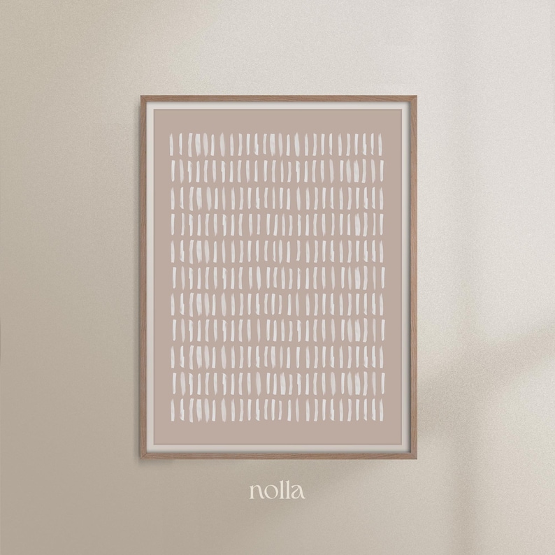 May include: A framed abstract print with a light brown background and a pattern of white brushstrokes. The print is framed in a natural wood frame. The word "nolla" is printed below the frame.