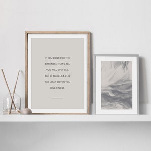 May include: Two framed prints on a white shelf. The print on the left is a quote that reads "If you look for the darkness that's all you will ever see, but if you look for the light often you will find it." The print on the right is a gray and white abstract design.