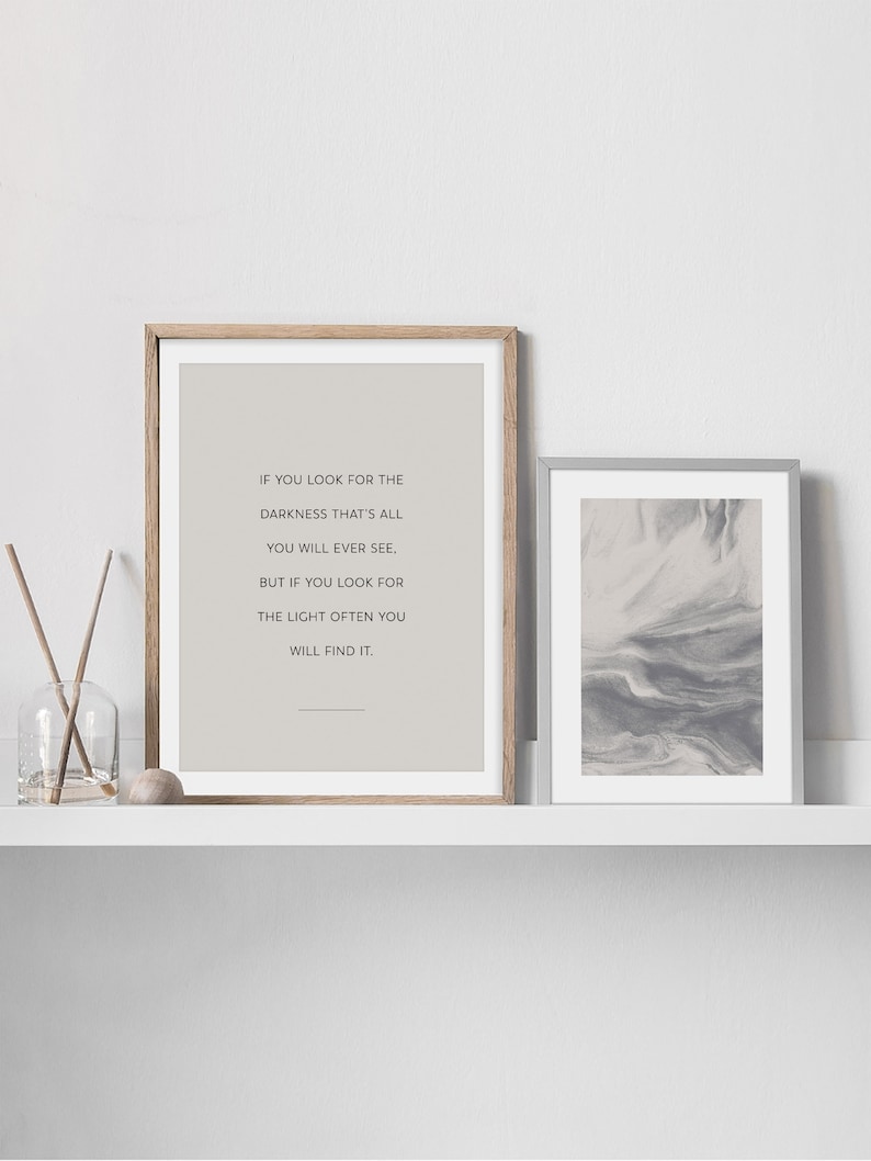 May include: Two framed prints on a white shelf. The print on the left is a quote that reads "If you look for the darkness that's all you will ever see, but if you look for the light often you will find it." The print on the right is a gray and white abstract design.