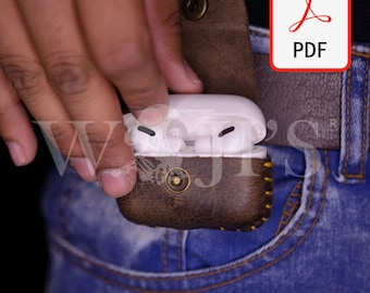 May include: A brown leather case with a stitched design and a gold button closure. The case is holding a white wireless earbud charging case.