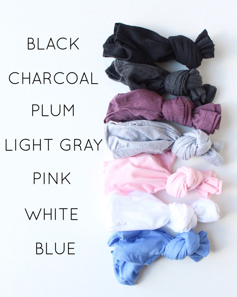 May include: A stack of eight t-shirts in different colors, including black, charcoal, plum, light gray, pink, white, and blue. The t-shirts are folded and tied in a knot.