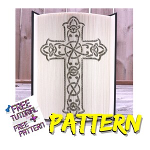 Può includere: Un libro bianco con una copertina nera è piegato in un design a croce celtica 3D. La croce è delineata in grigio e ha un motivo decorativo. Il testo "PATTERN" è in lettere gialle nella parte inferiore dell'immagine.